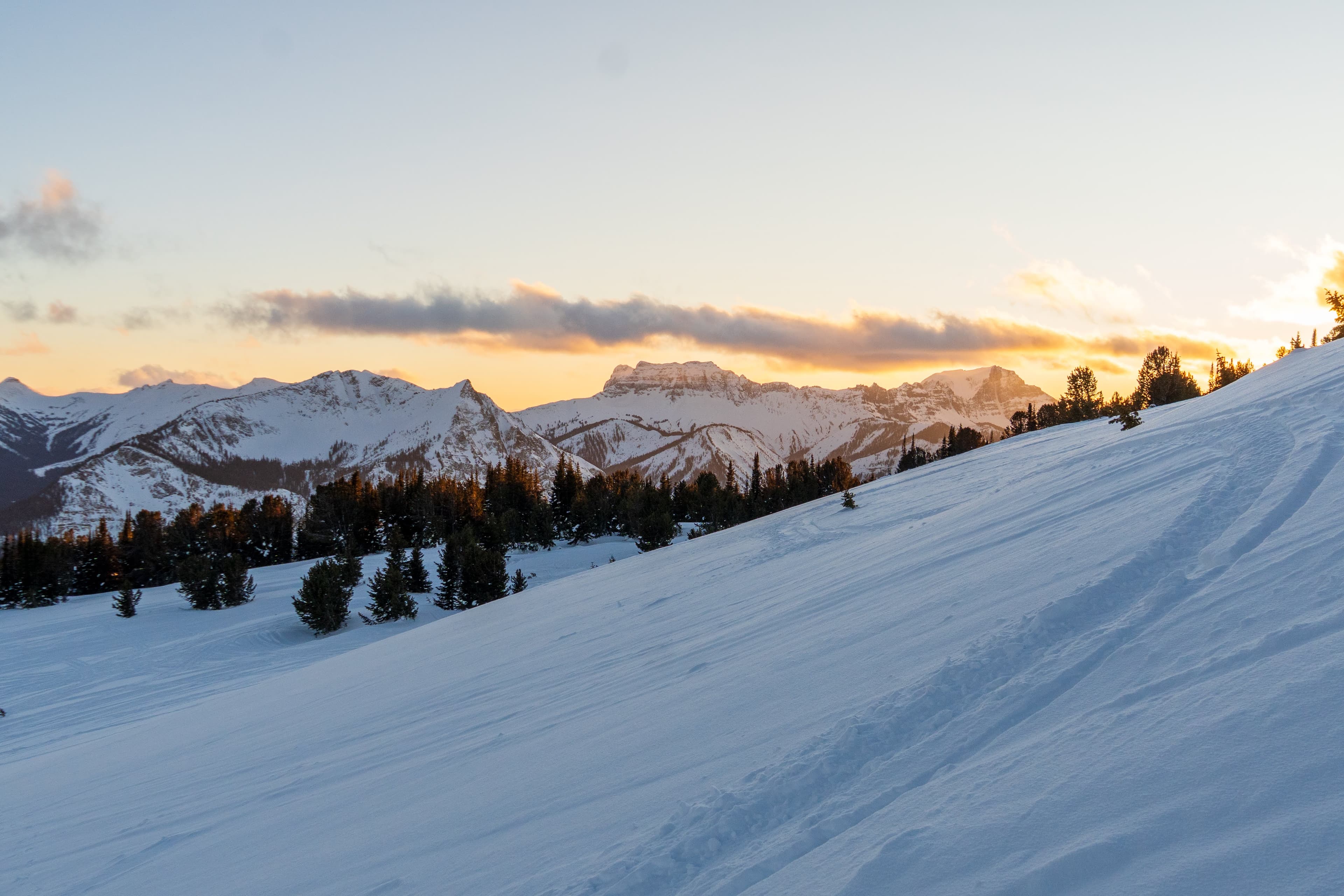 Sunrise light over a snowy mountain horizon.