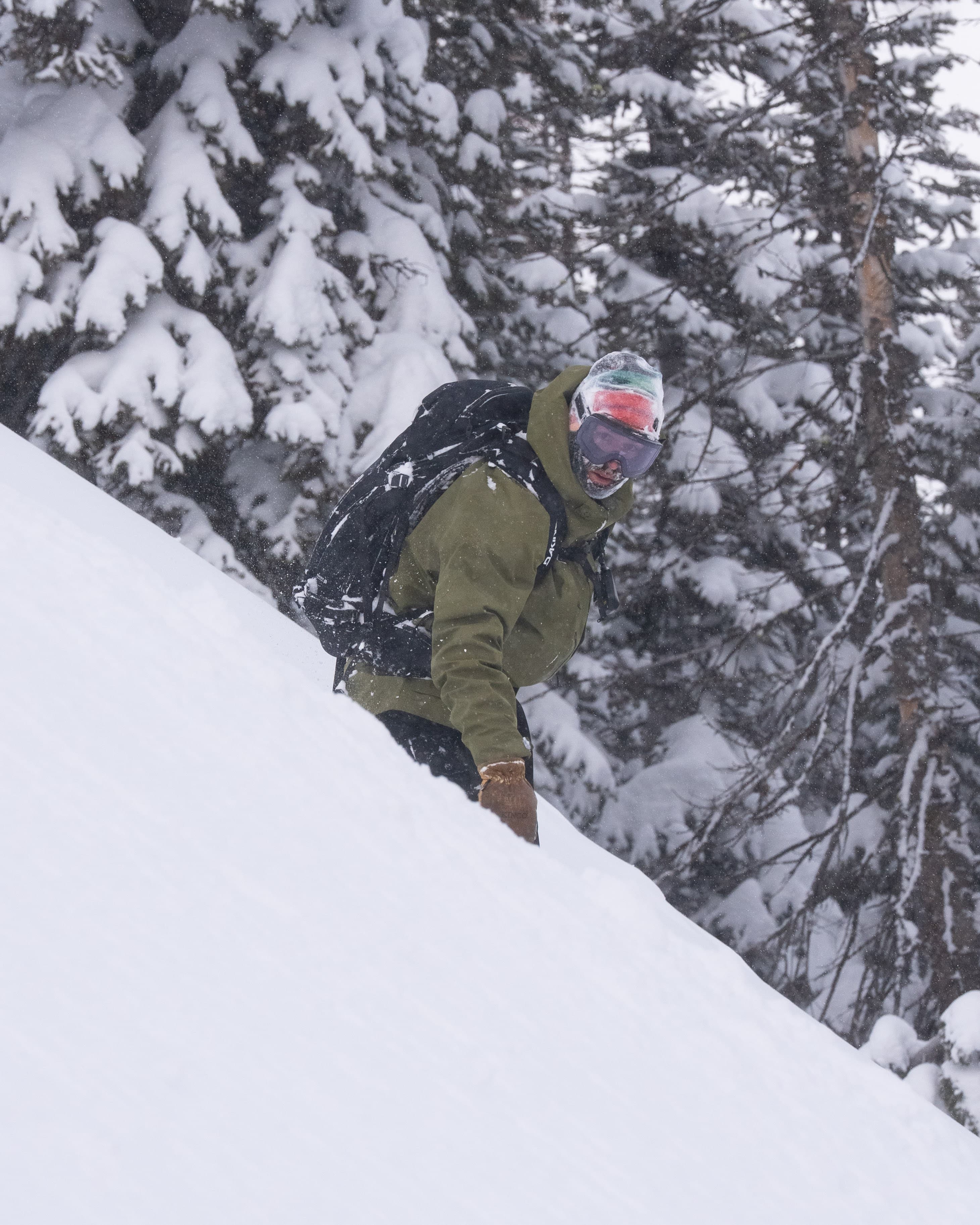 A rider moving through falling snow in the trees near the Roost.