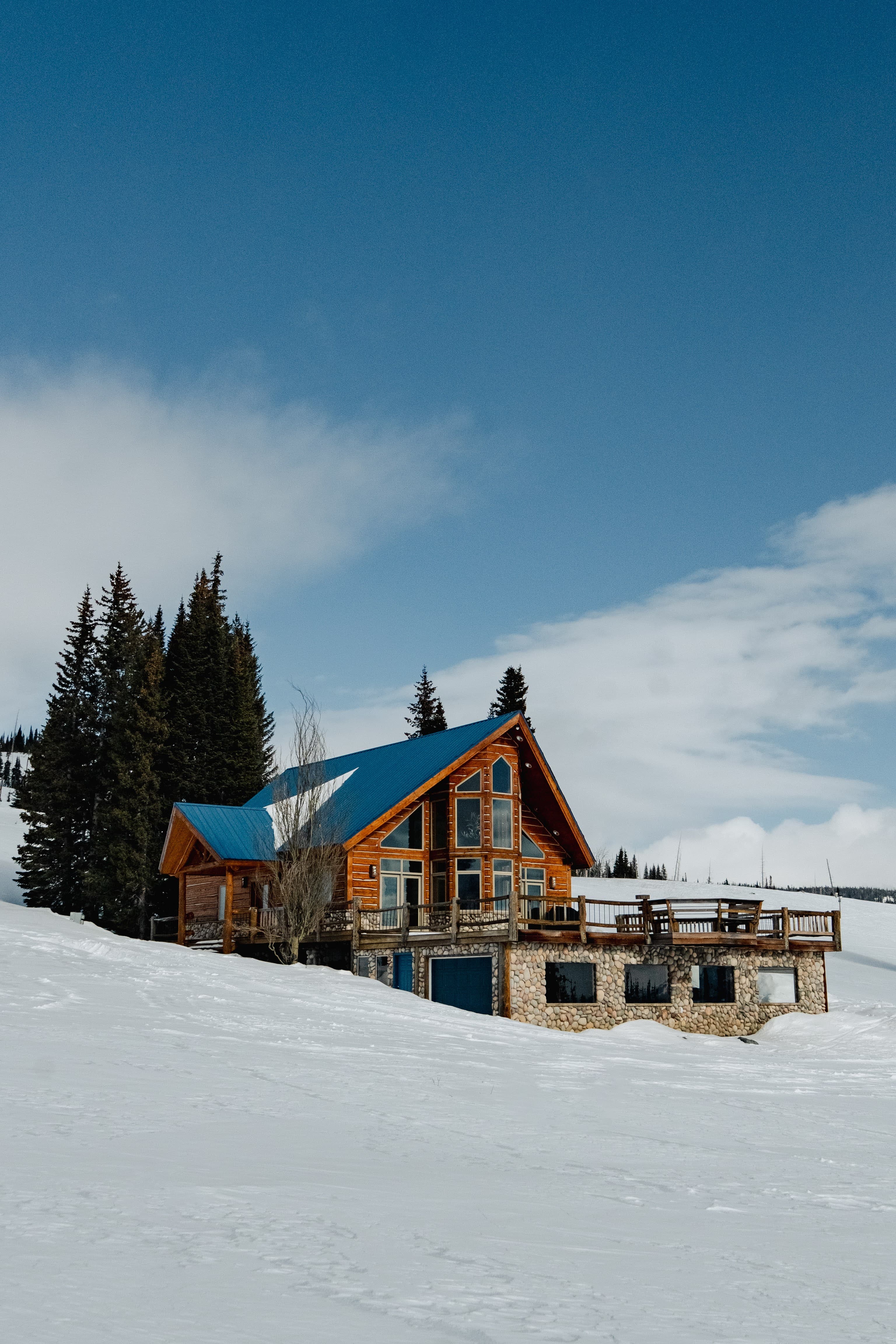 Pilots Roost A-frame lodge with a blue metal roof, snow-covered approach, and winter sky.